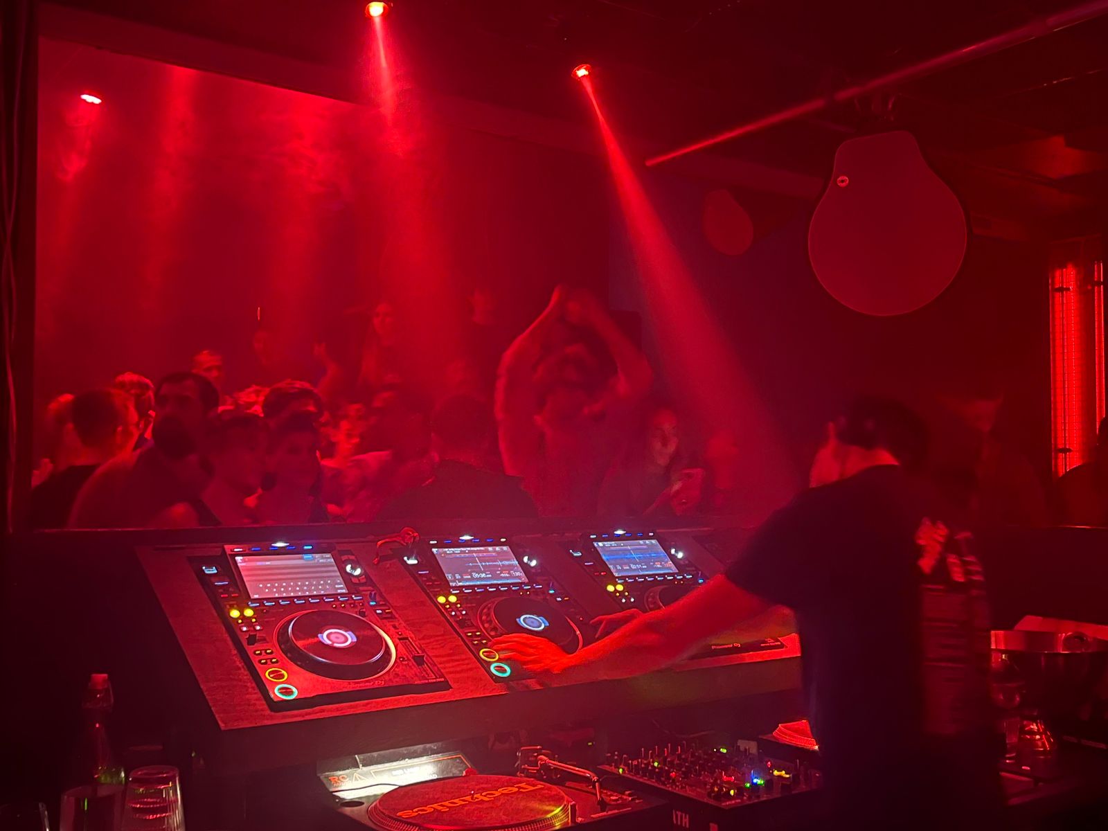 DJ playing to a packed, energetic nightclub dancefloor